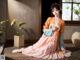 A woman in a pink and orange kimono sitting on a wooden floor.