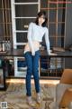 A woman standing in front of a desk in a room.