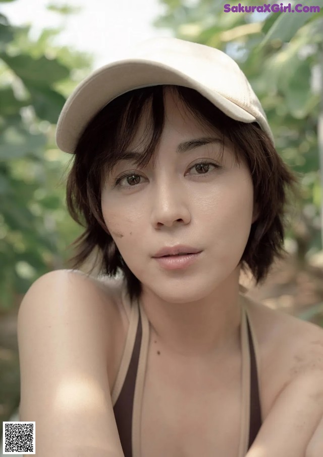 A woman wearing a baseball cap sitting on a bench.