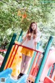 A young woman standing on a colorful playground slide.