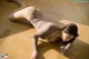 A woman laying on the floor in a brown bodysuit.