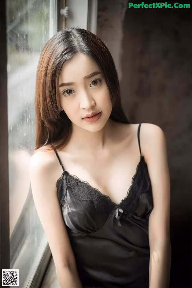 A woman in a black lingerie leaning against a window.