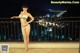 A woman in a bikini standing on a balcony at night.