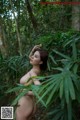 A naked woman standing in the middle of a forest.