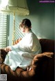 A woman sitting on a chair in front of a lamp.