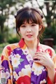 A woman in a colorful kimono poses for a picture.