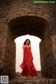 A woman in a red dress standing in an archway.