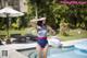 A woman in a bathing suit standing next to a swimming pool.