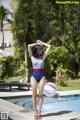 A woman in a bathing suit standing by a swimming pool.