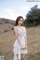 A woman in a white dress standing in a field.