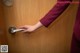 A woman's hand is opening a door with a handle.