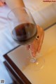 A woman holding a glass of red wine on a table.