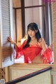 A woman in a red lingerie leaning against a window.