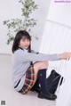 A young woman in a school uniform sitting on the floor.