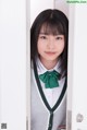 A young woman in a school uniform peeking out from behind a door.