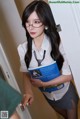 A woman in a school uniform holding a book.