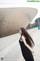 A woman in a black dress standing in front of a building.