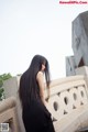 A woman in a black dress standing on a stone wall.