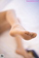 A close up of a person's bare feet on a bed.