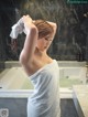 A woman in a white towel standing in a bathroom.