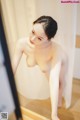 A naked woman standing in front of a mirror.