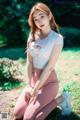 A woman in a white top and pink leggings sitting on the ground.