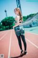 A woman in a sports bra top and leggings standing on a track.