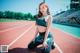 A woman sitting on a running track with her legs crossed.