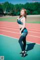 A woman in a sports bra top and leggings standing on a track.