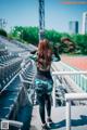 A woman standing on a stadium with her back to the camera.