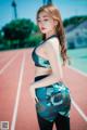 A woman in a sports bra top and leggings posing on a track.