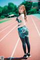 A woman in a sports bra top and leggings standing on a track.