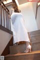 A woman in a white dress is walking up some stairs.