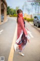 A woman in a red and white dress is walking down the street.