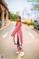 A woman wearing a red scarf standing in the middle of a street.