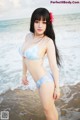 A woman in a blue bikini standing on the beach.