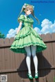 A girl in a green dress standing on a wooden fence.