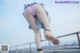 A woman in a pink panties is bending over on a railing.