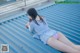 A woman laying on top of a blue metal roof.