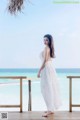 A woman in a white dress standing on a wooden deck.