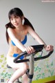 A woman in a blue bikini riding a stationary bike.