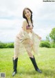 A woman in a bikini and cowboy boots posing in a field.