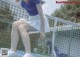 A woman sitting on a tennis court with her legs crossed.