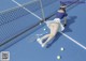 A woman laying on a tennis court with a tennis racket.