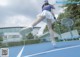 A woman in a blue shirt and white skirt playing tennis.