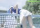 A woman leaning over a tennis net on a tennis court.