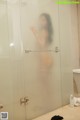 A woman standing in a bathroom next to a shower.