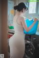 A woman in a white dress standing next to a washing machine.