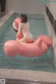 A woman sitting on an inflatable flamingo in a pool.