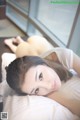 A woman laying on top of a bed next to a window.